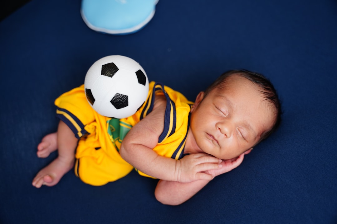 Newborn baby sleeping with a soccer ball on back