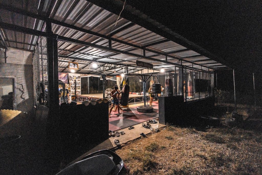 People exercising in a dimly lit outdoor gym at night.