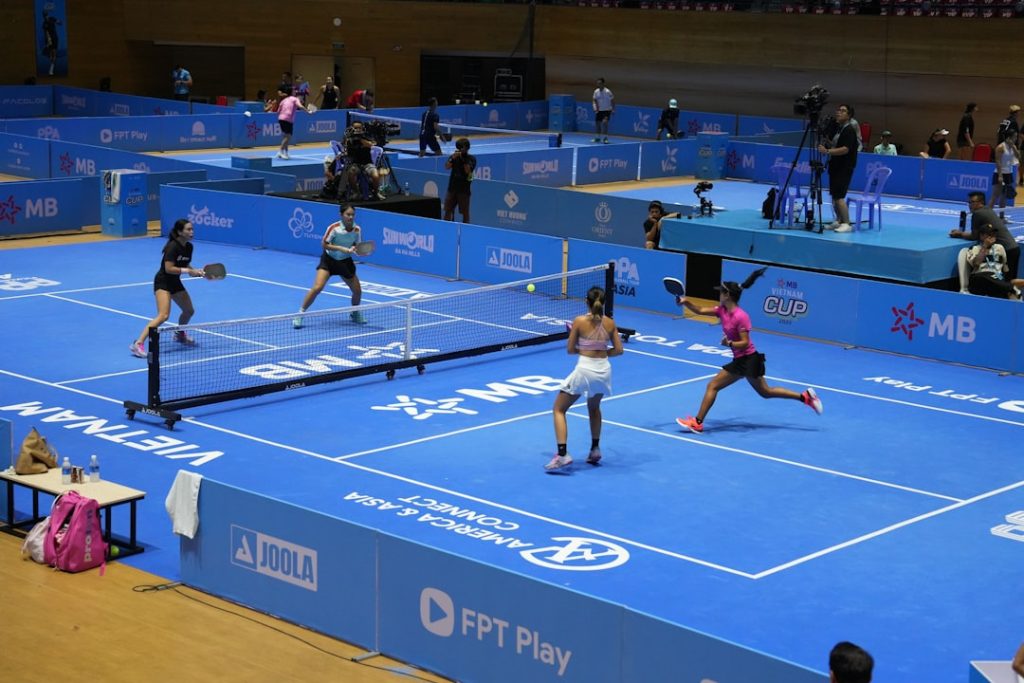 Players compete in a pickleball match on a blue court.
