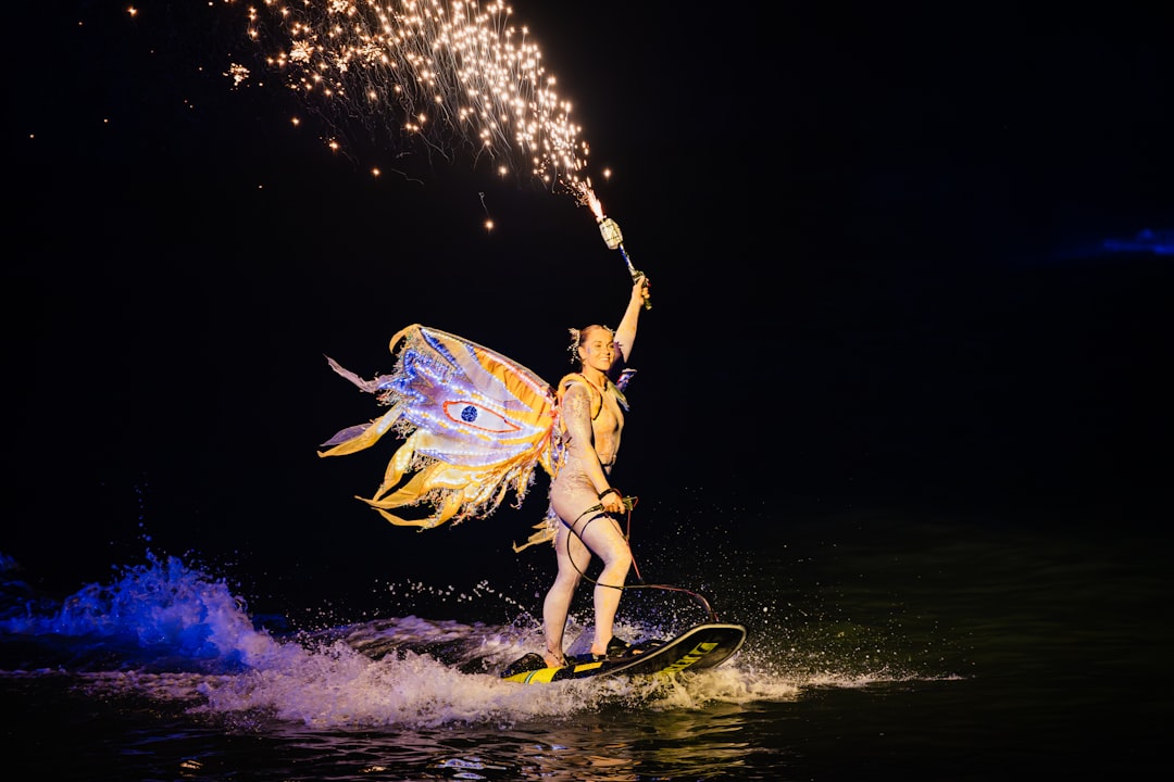 Performer with wings rides a wakeboard at night
