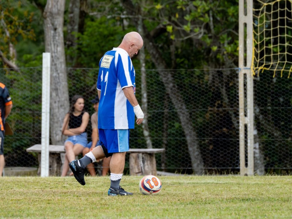 Man in blue and white jersey kicks soccer ball