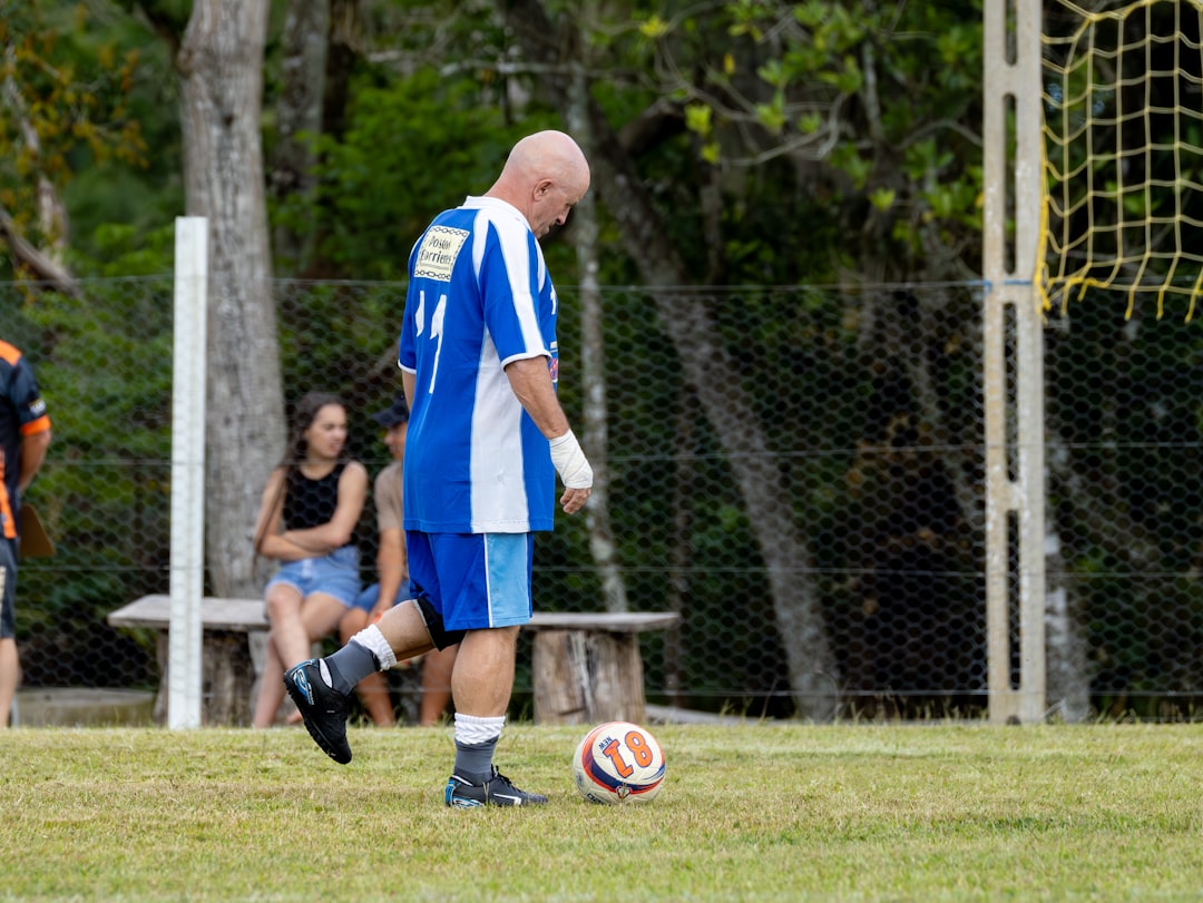 Man in blue and white jersey kicks soccer ball