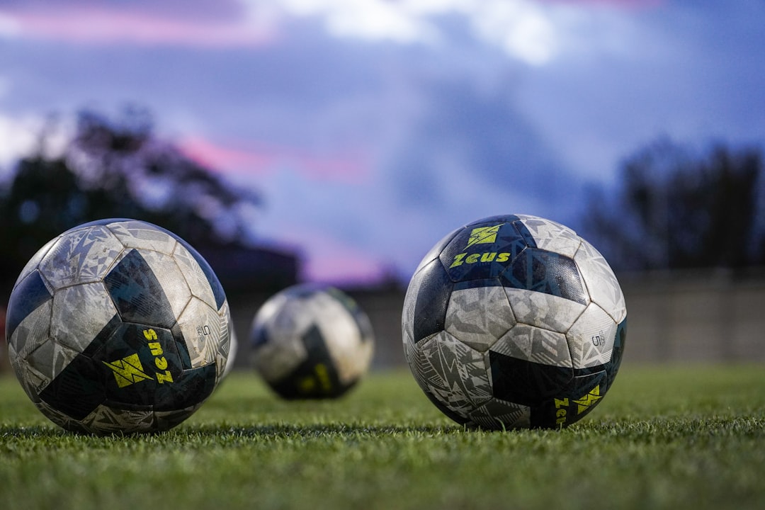Three soccer balls resting on green grass