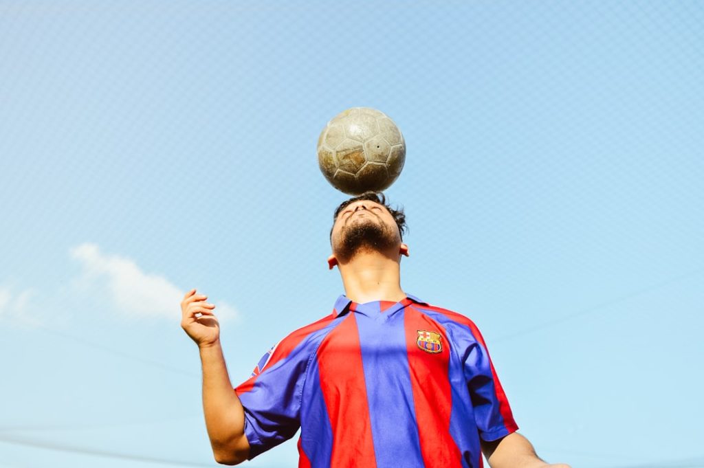 A man is balancing a soccer ball on his head