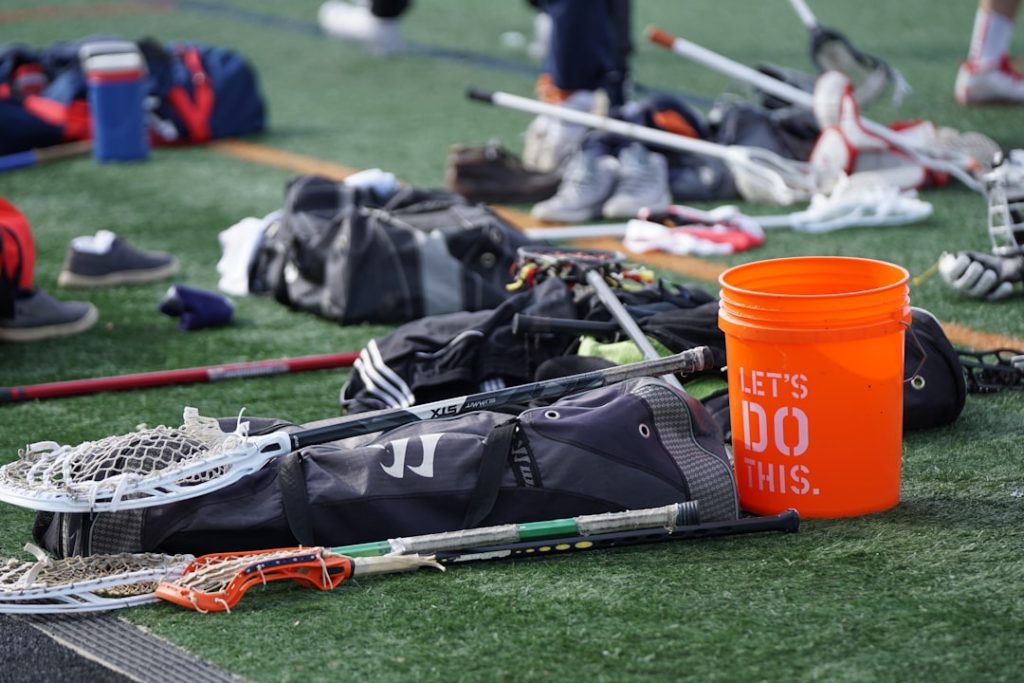 orange plastic industrial bucket beside lacrosse sticks