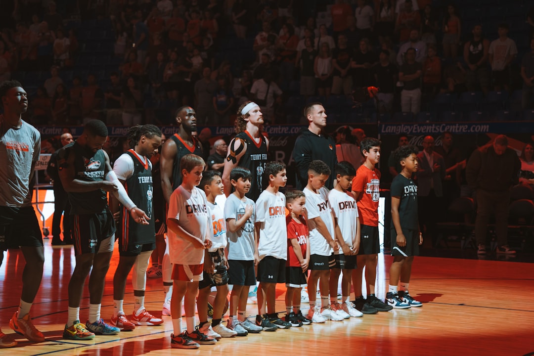 Basketball players and kids stand on a court.