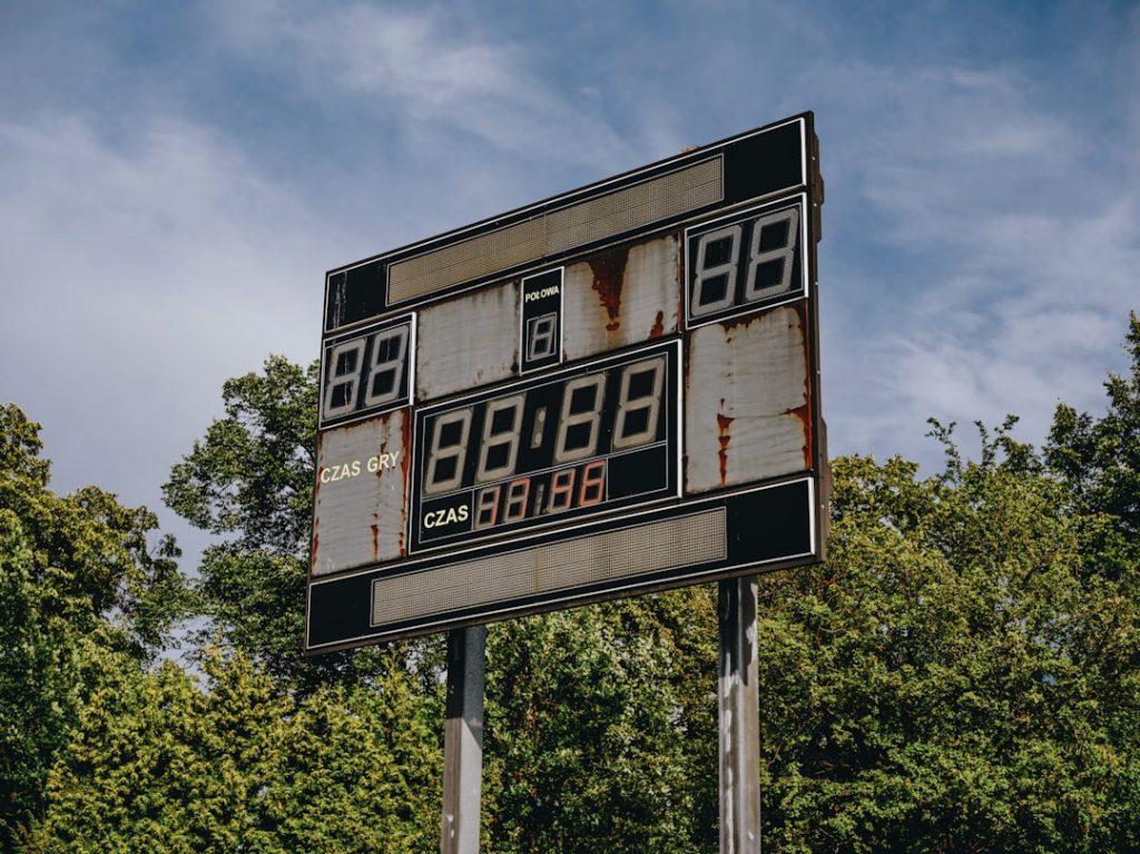 an old gas station sign with trees in the background