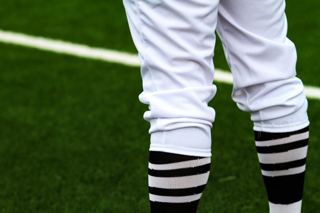 a person's legs in a white uniform on a green field