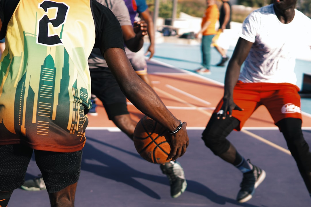 man in white and green jersey shirt and black shorts running on road during daytime