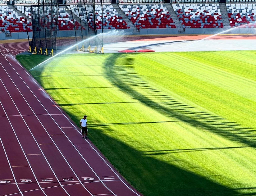 Stadium sprinklers watering the field during the day.