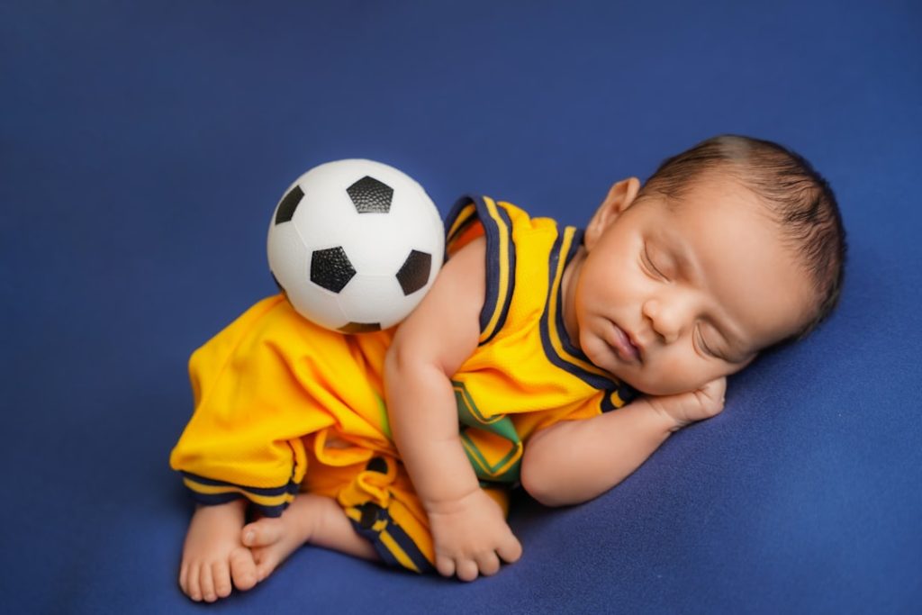 Newborn baby sleeping with a soccer ball