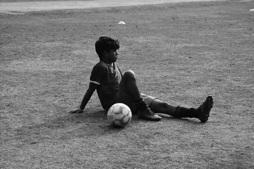 A young boy sitting on the ground with a soccer ball