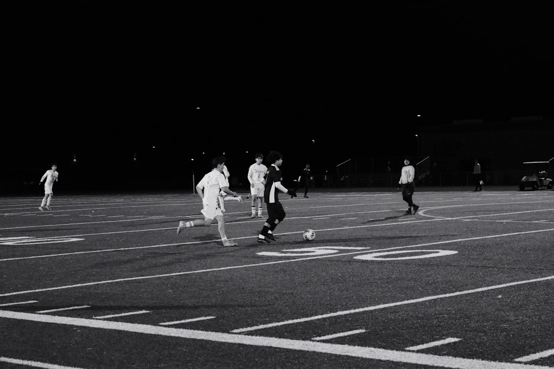 Soccer players compete on a field at night