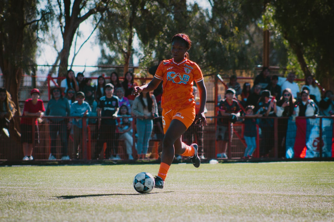 Soccer player dribbles the ball on a sunny field.