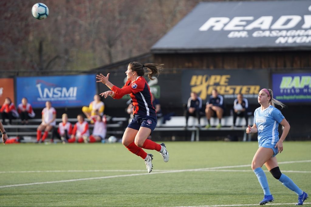 woman jumping about to catch soccer ball