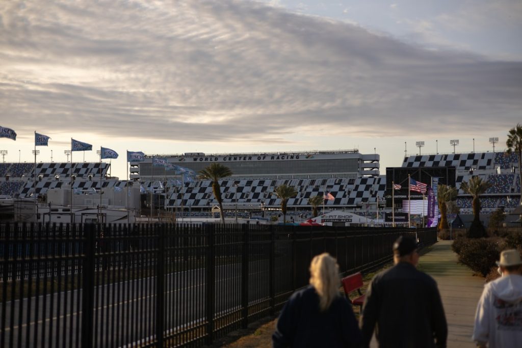People walk towards a grandstand at a racetrack.