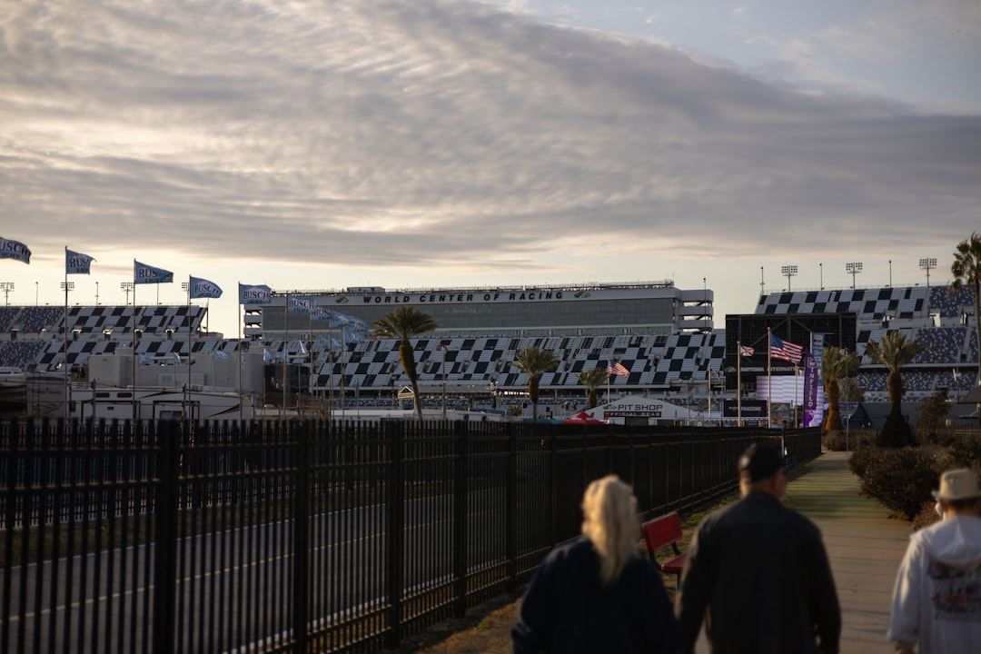 People walk towards a grandstand at a racetrack.