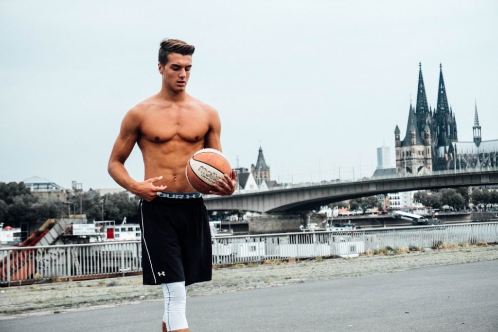 topless man in black pants holding basketball