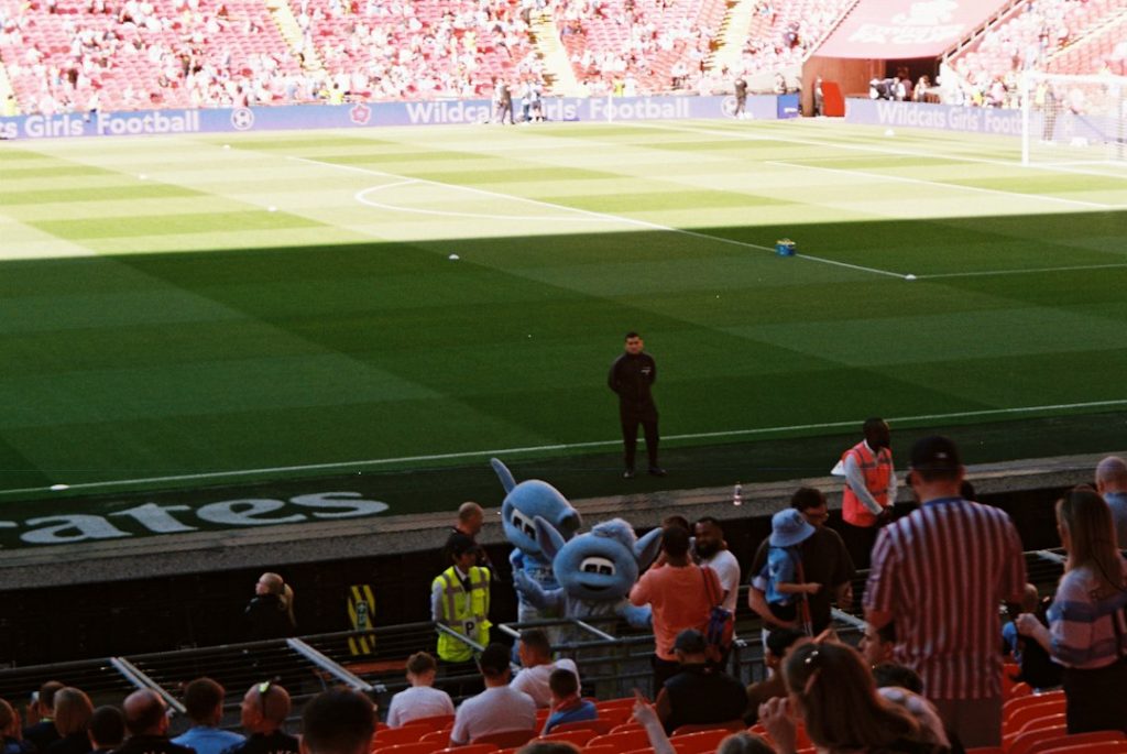 Mascot and spectators at a sunny outdoor stadium event