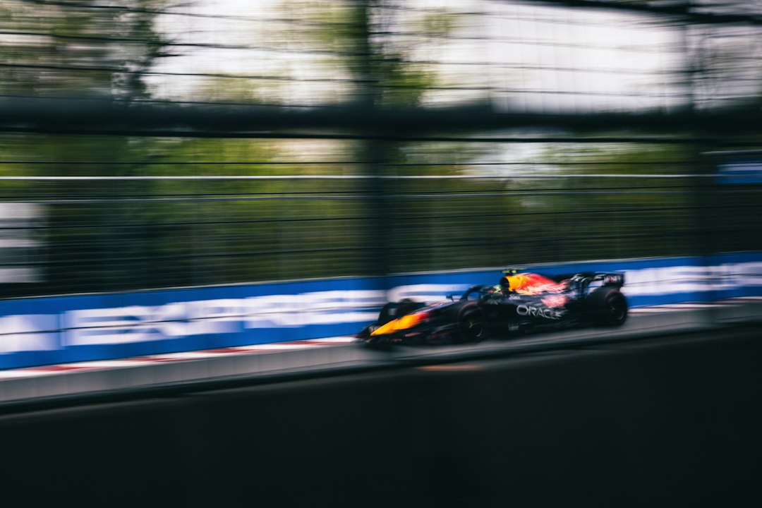 A high-speed race car blurs past a blue track barrier