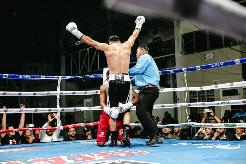 Boxer celebrates victory with arms raised in the ring