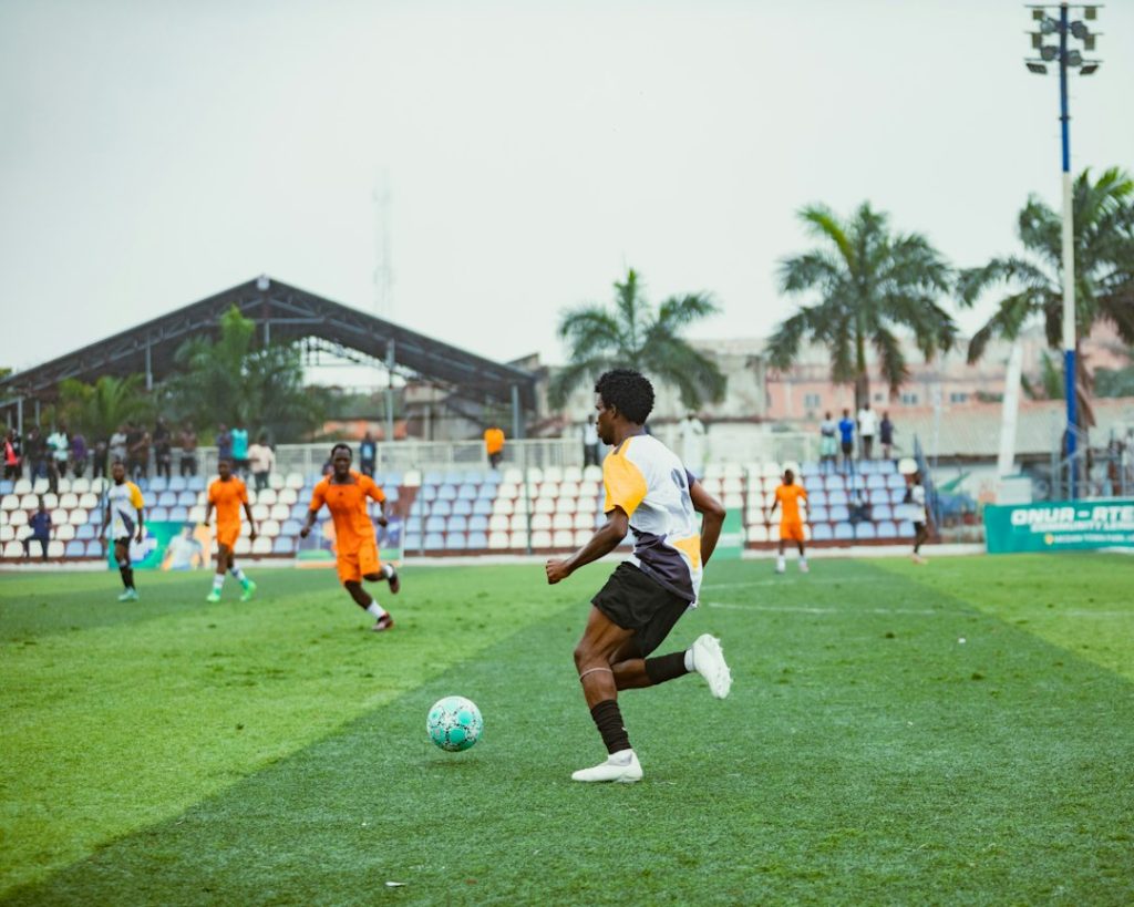 A soccer player dribbling a ball on a green field during a match