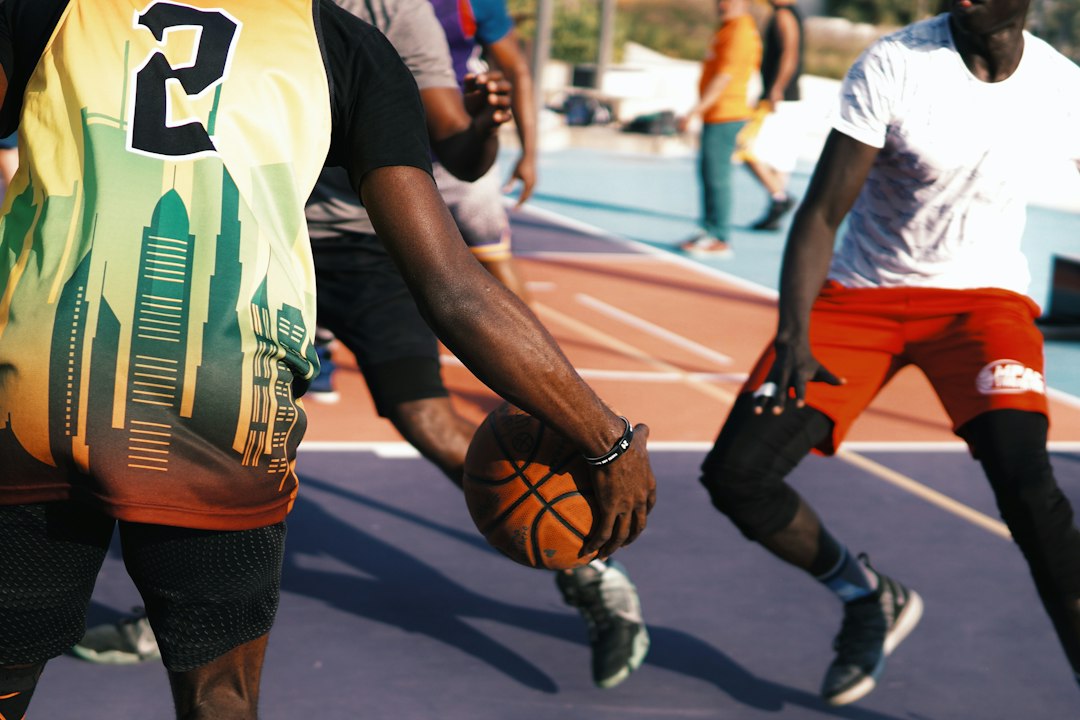 man in white and green jersey shirt and black shorts running on road during daytime