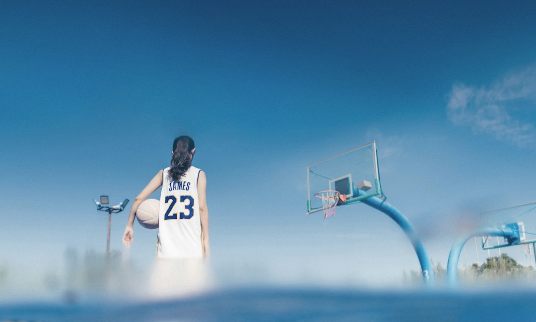 a woman holding a basketball standing next to a basketball hoop